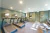 Gym facility, three treadmills and two elliptical machines, mint green walls and natural light from windows