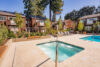 Spa hot tub at apartment complex, two-story buildings with cedar siding, balconies overlooking pool area, landscaping, communal recreational space